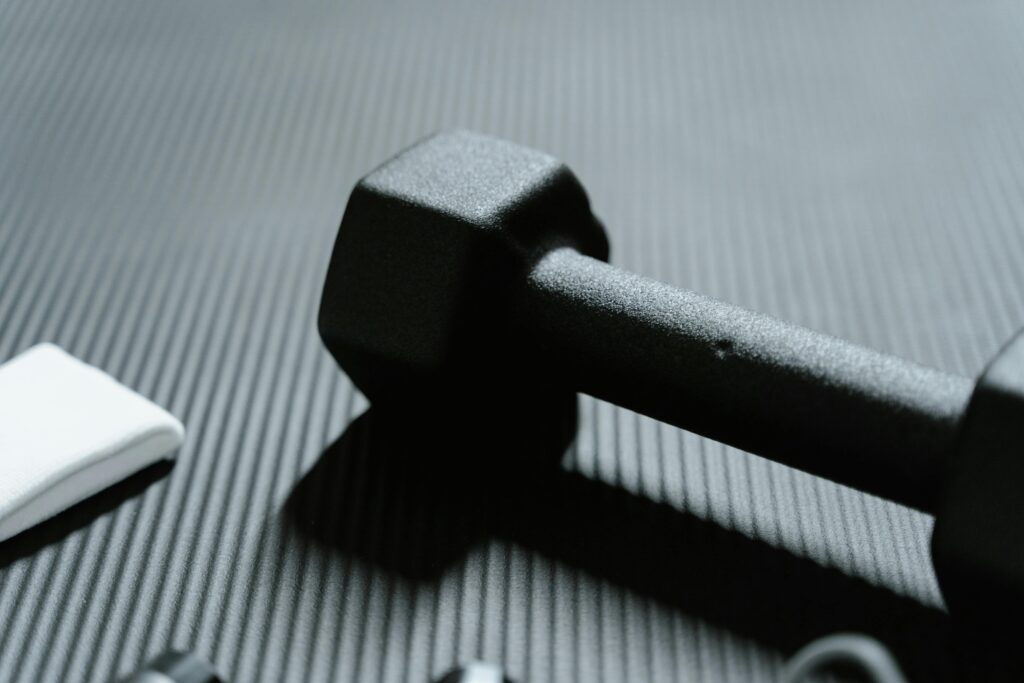 Detailed view of a black dumbbell on textured mat for fitness workout